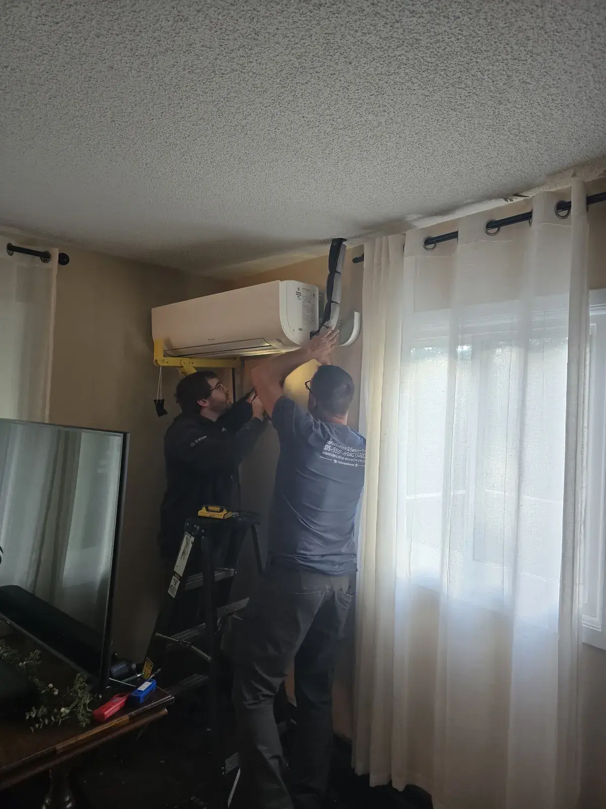 Two Iowa All Pro technicians mounting a ductless mini-split head