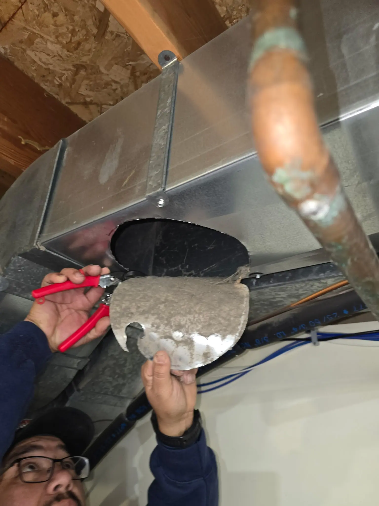 Technician fitting a damper into new sheet metal ductwork